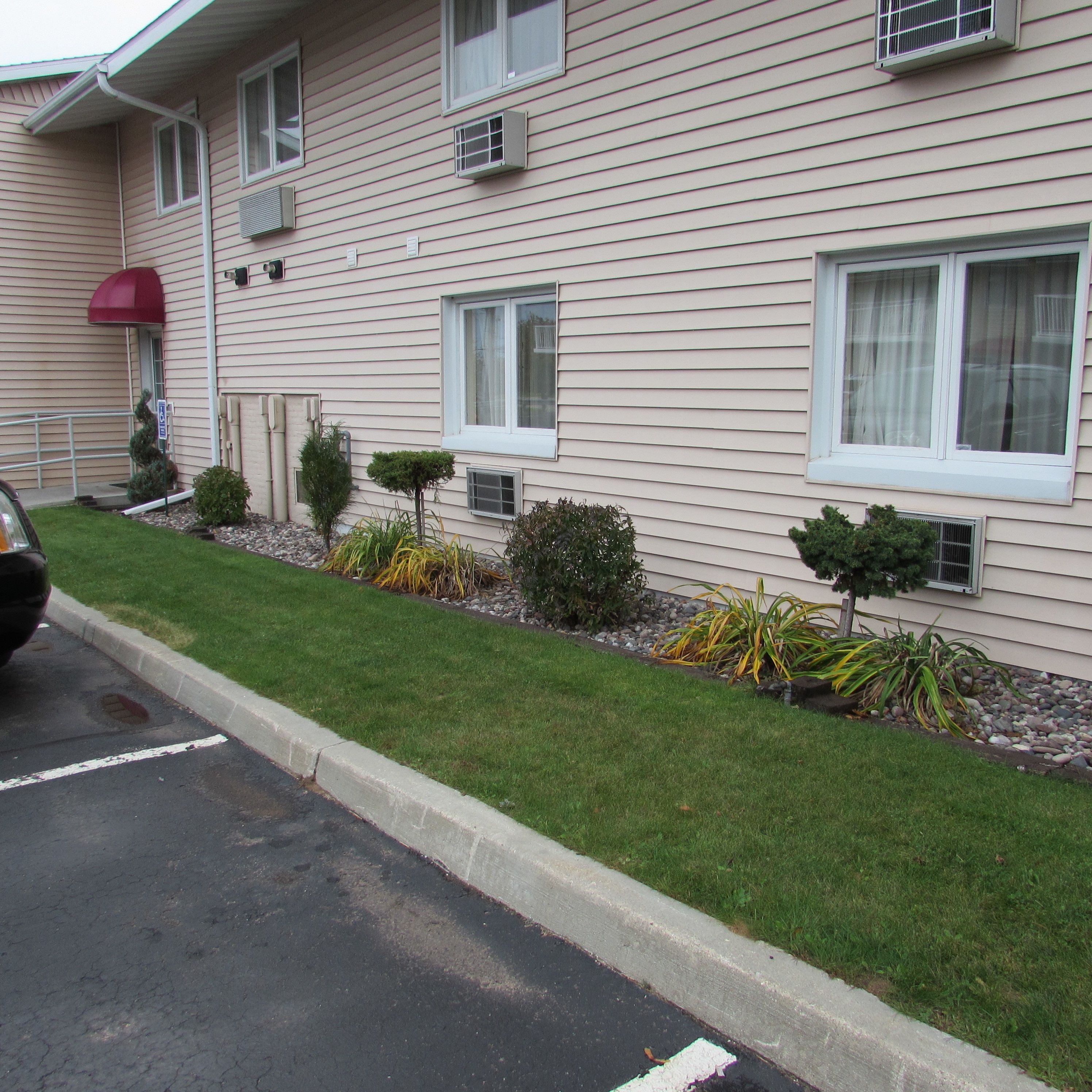 A two-story building with a flat roof, multiple windows, and a parking area with a curb.