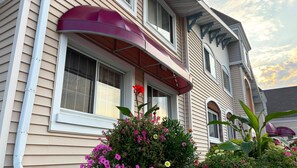 A two-story house with a red awning over the front door, a window with a white frame, and a small garden with various flowers. - Magnuson Grand Pioneer Inn and Suites (Escanaba)