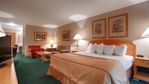 A hotel room with a bed, a desk, a chair, a television, and two lamps. - Magnuson Grand Pioneer Inn and Suites (Escanaba)