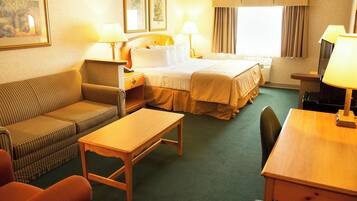 Ein Hotelzimmer mit Bett, Sofa, Tisch und zwei Lampen.