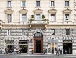 Un edificio storico con un ingresso centrale, numerose finestre e negozi al piano terra.
