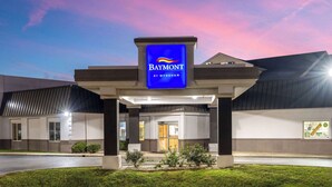 A Baymont hotel entrance with a prominent blue sign, a covered walkway, and a landscaped area in front. - Baymont by Wyndham Indianapolis East (Indianapolis)