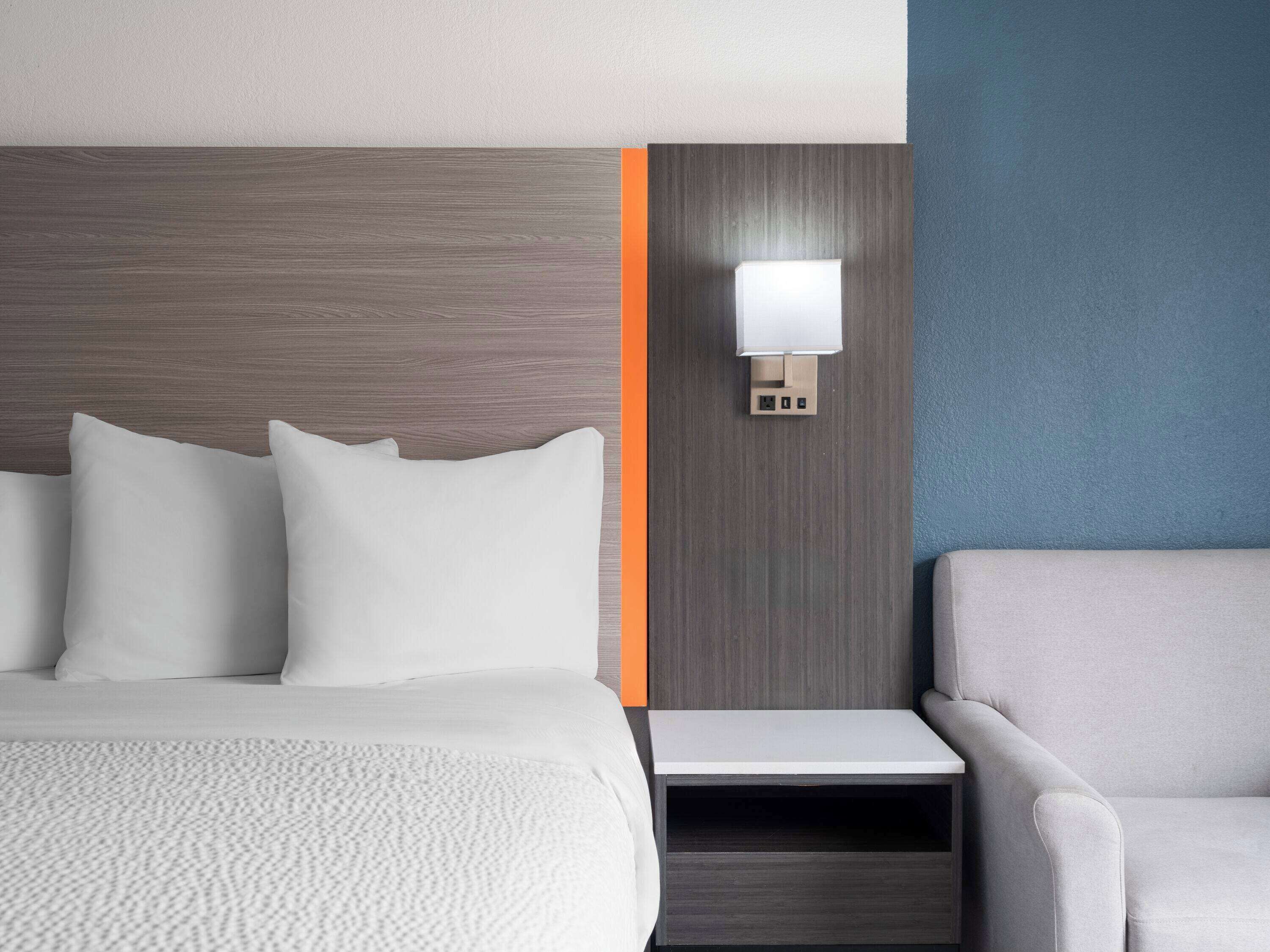 Une chambre d’hôtel avec un lit, une table de chevet, une lampe et une chaise.