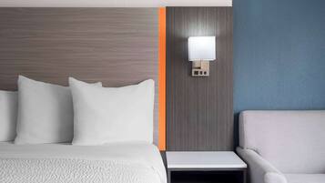 Une chambre d’hôtel avec un lit, une table de chevet, une lampe et une chaise.