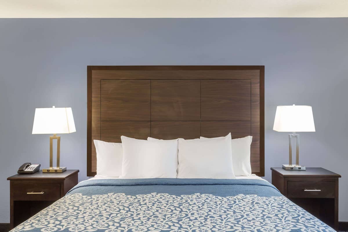 Quarto de hotel com uma cama grande, duas mesas de cabeceira, um criado-mudo com telefone e cabeceira.