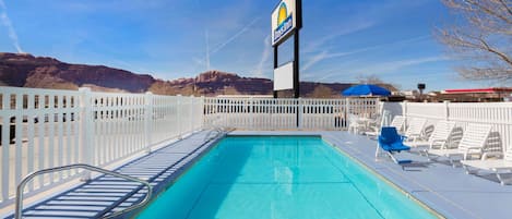 Una piscina al aire libre, sillones reclinables de piscina