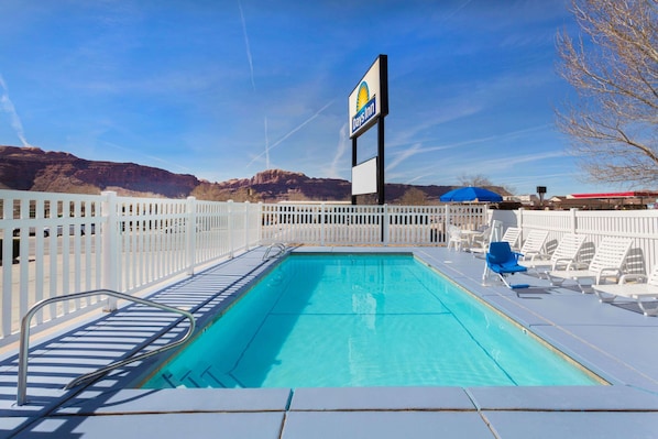 Una piscina al aire libre, sillones reclinables de piscina