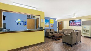 A reception area with a counter, chairs, a television, and a refrigerator.