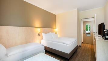 Una habitación de hotel con cama, sofá, una mesita con fruta y televisión.