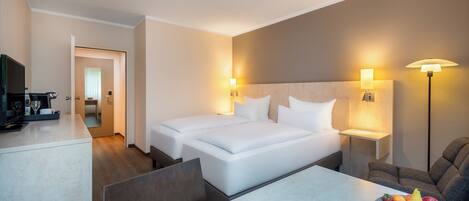 Habitación de hotel con cama, mesitas de noche, escritorio con televisor y frutero.