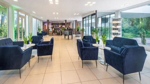 Un moderno vestíbulo de hotel con zona de bar, asientos y grandes ventanales.