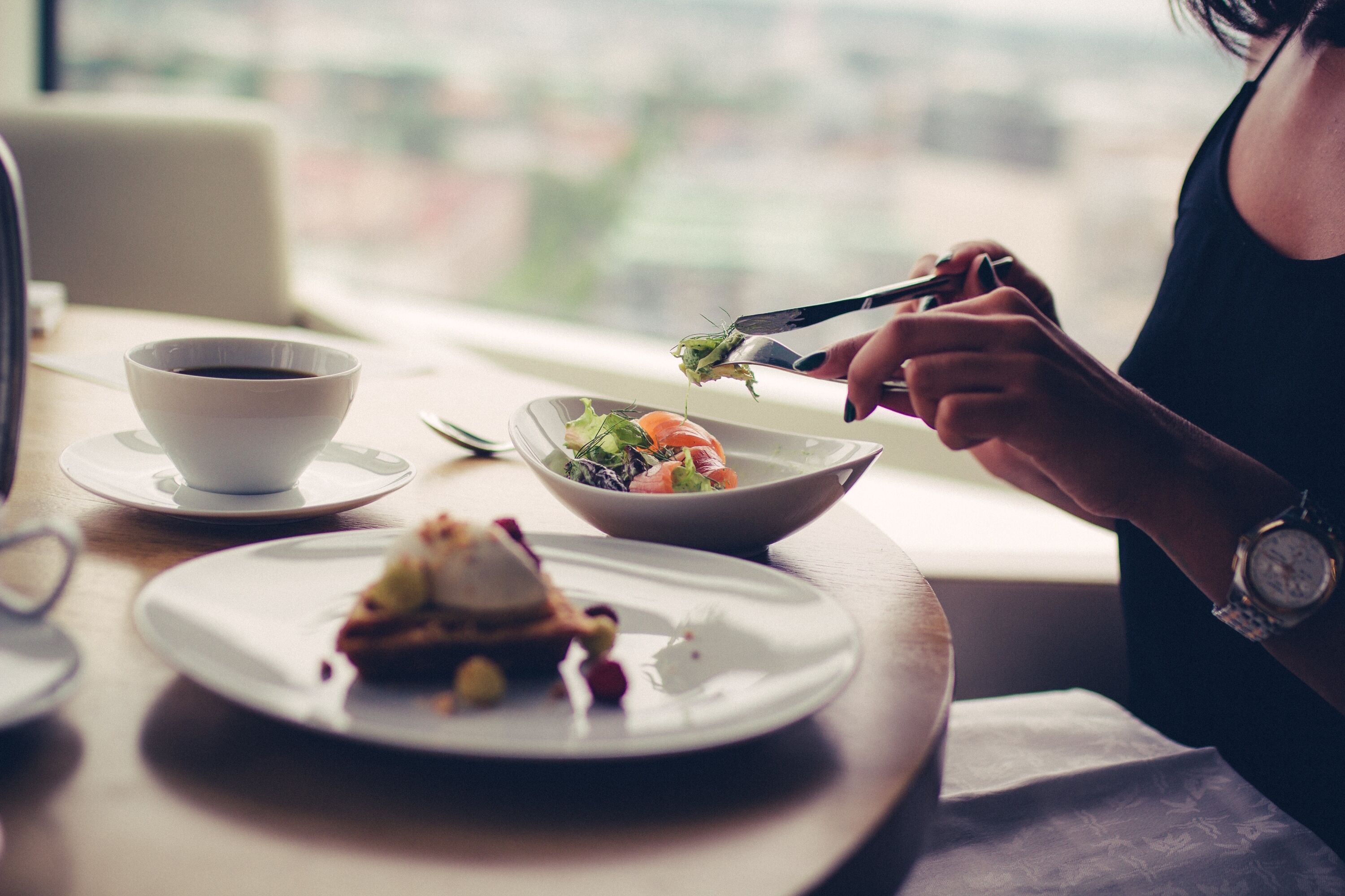 A dining table with a cup of coffee, a bowl of salad, and a plate with food.