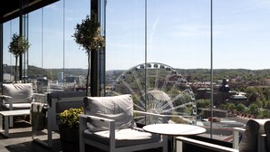 Un espace extérieur moderne, aménagé avec des meubles blancs et offrant une vue sur une grande roue.
