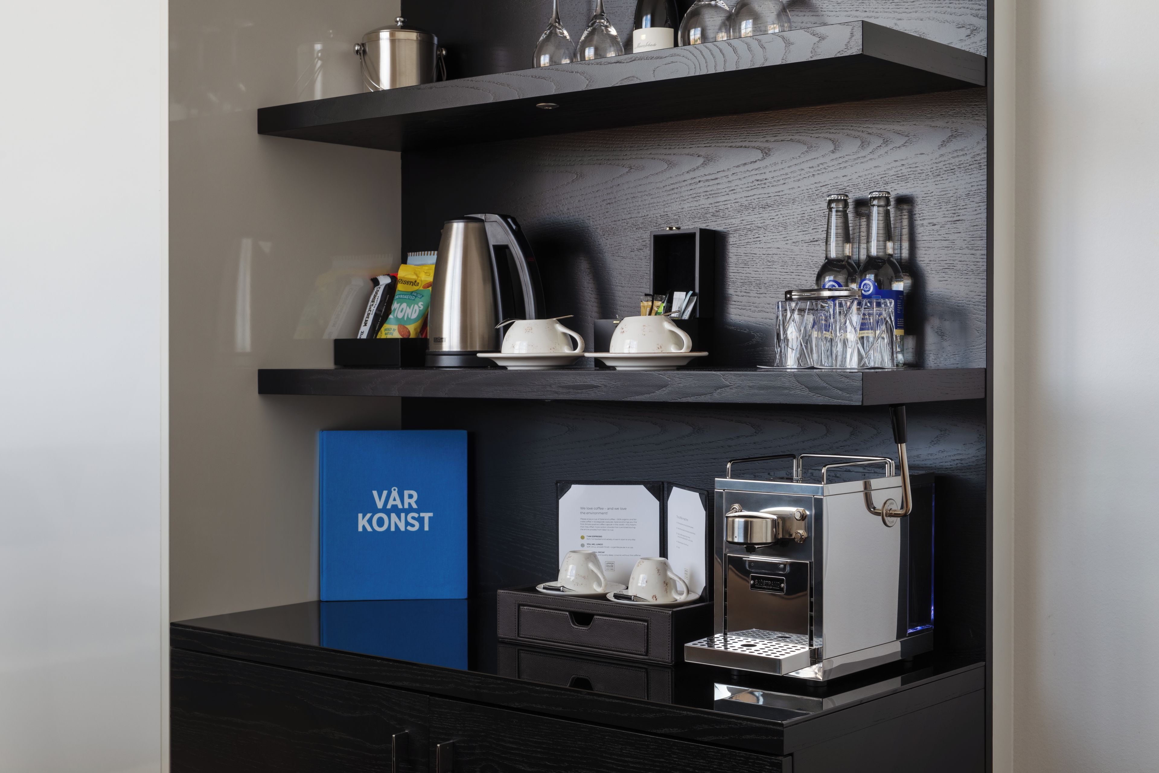 Une cuisine moderne équipée d’une machine à café, d’une bouilloire et d’un support pour capsules de café.