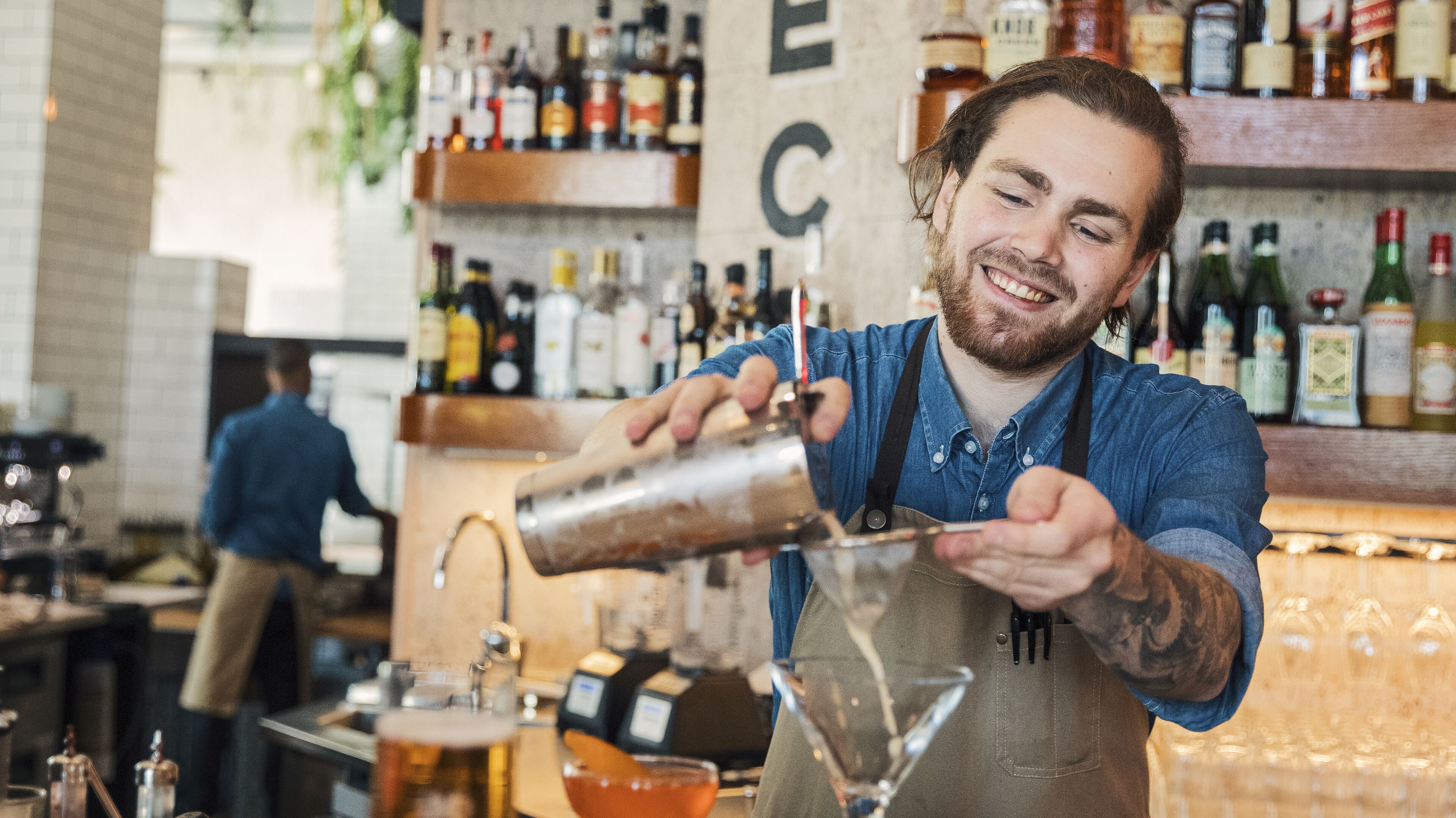 A bartender pouring a drink into a glass.