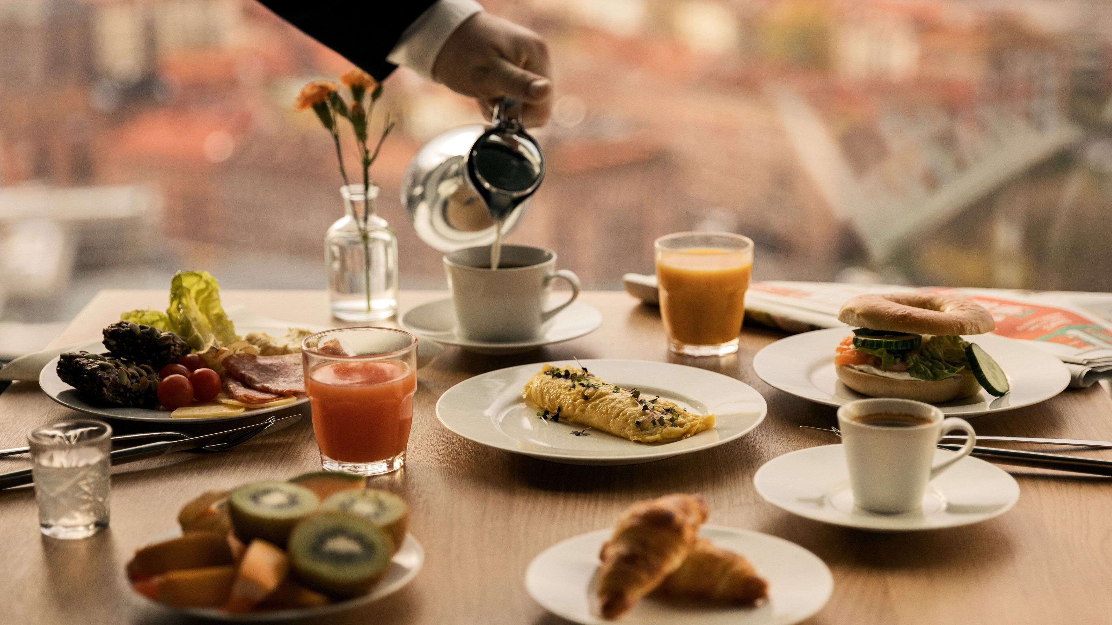 Una mesa de desayuno con diferentes alimentos y bebidas, como huevos, tostadas y un muffin.