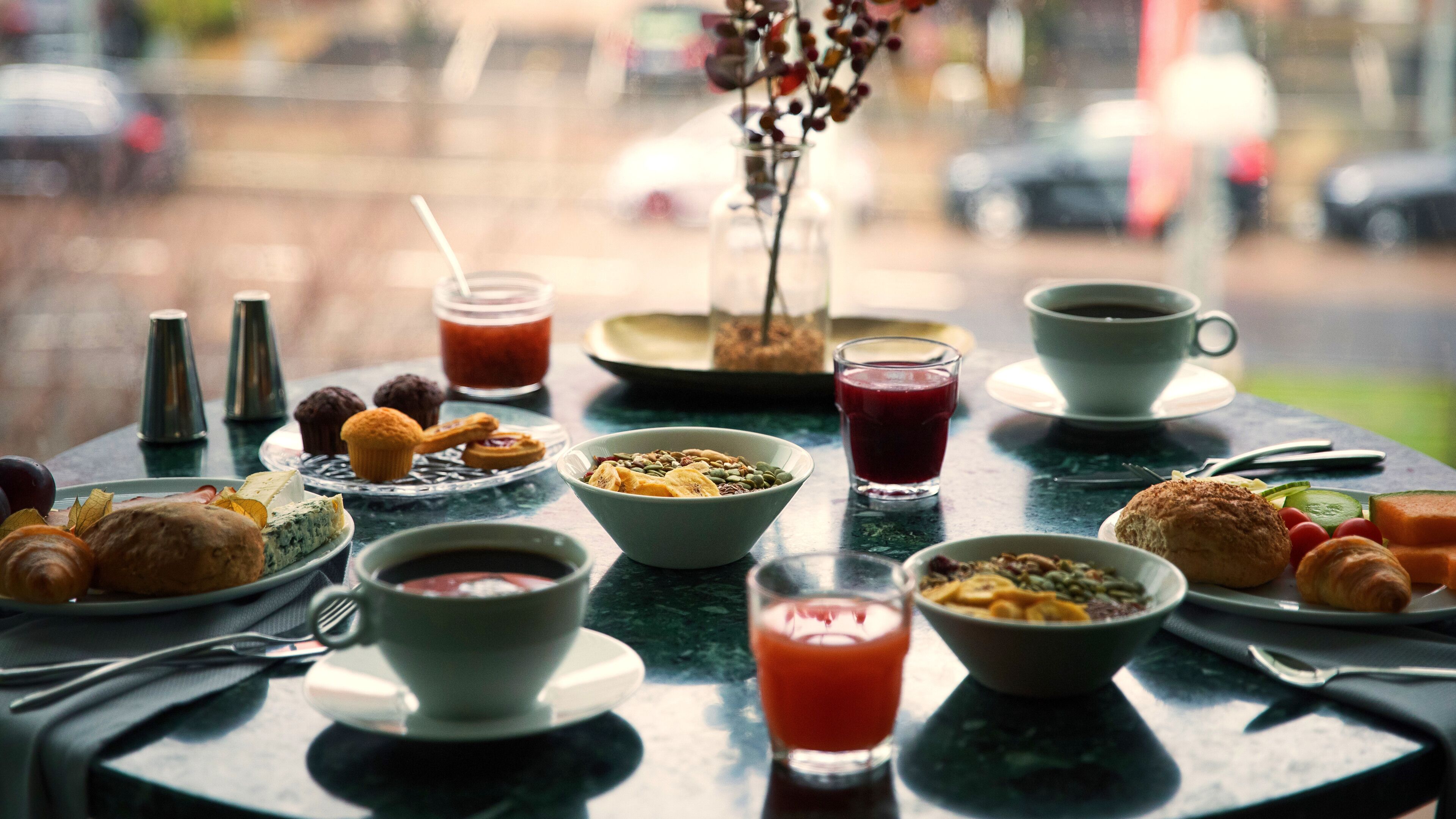 A breakfast table with various food items and drinks, including pastries, fruits, and beverages.