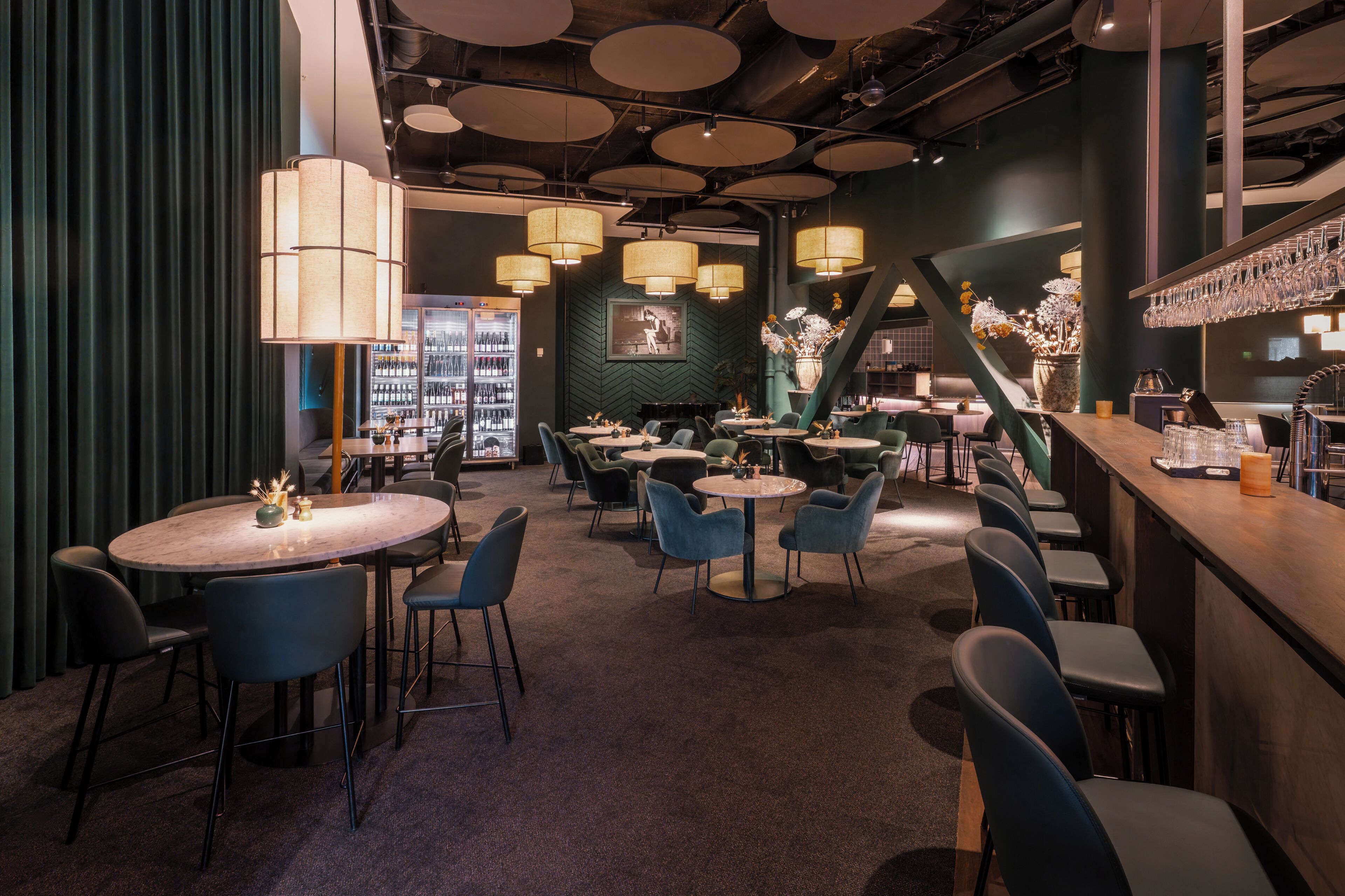 A restaurant interior with round tables, chairs, and a bar area.