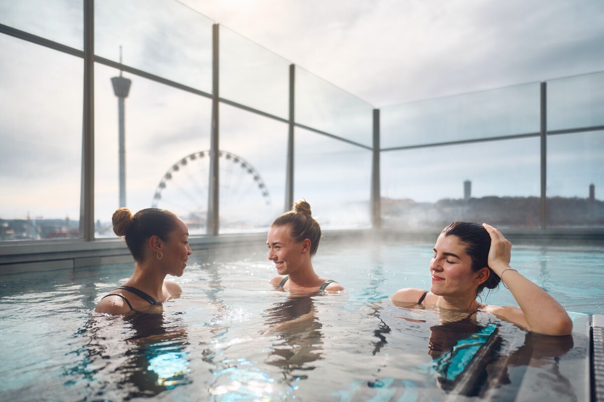 A pool area with large windows and a Ferris wheel in the background.