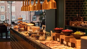 A buffet with various food items and a view of a brick building in the background.