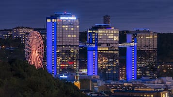 En stadsbild i nattljus med upplysta byggnader, inklusive ett pariserhjul och hotellkomplexet ”Gothia Towers”.