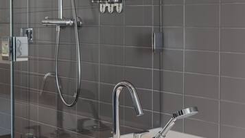 Un baño moderno con cabina de ducha de vidrio, un lavabo blanco e instalaciones cromadas.