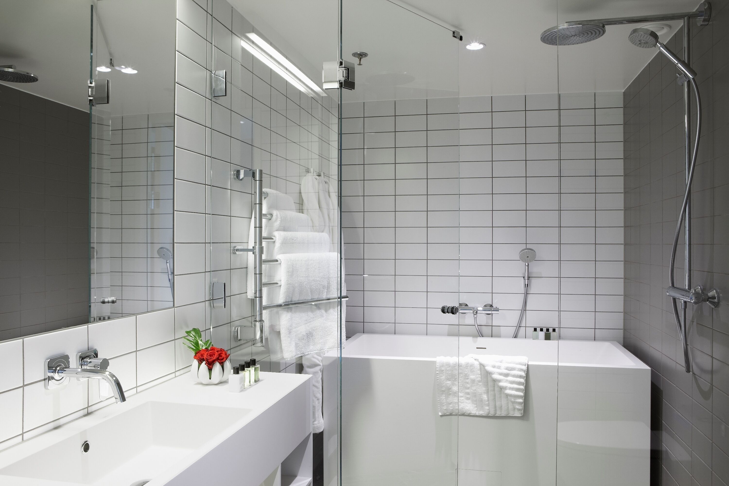 A modern bathroom with a glass-enclosed shower, a white sink, and a large mirror.
