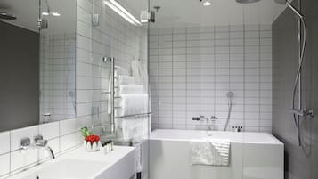 A modern bathroom with a glass-enclosed shower, a white sink, and a large mirror.