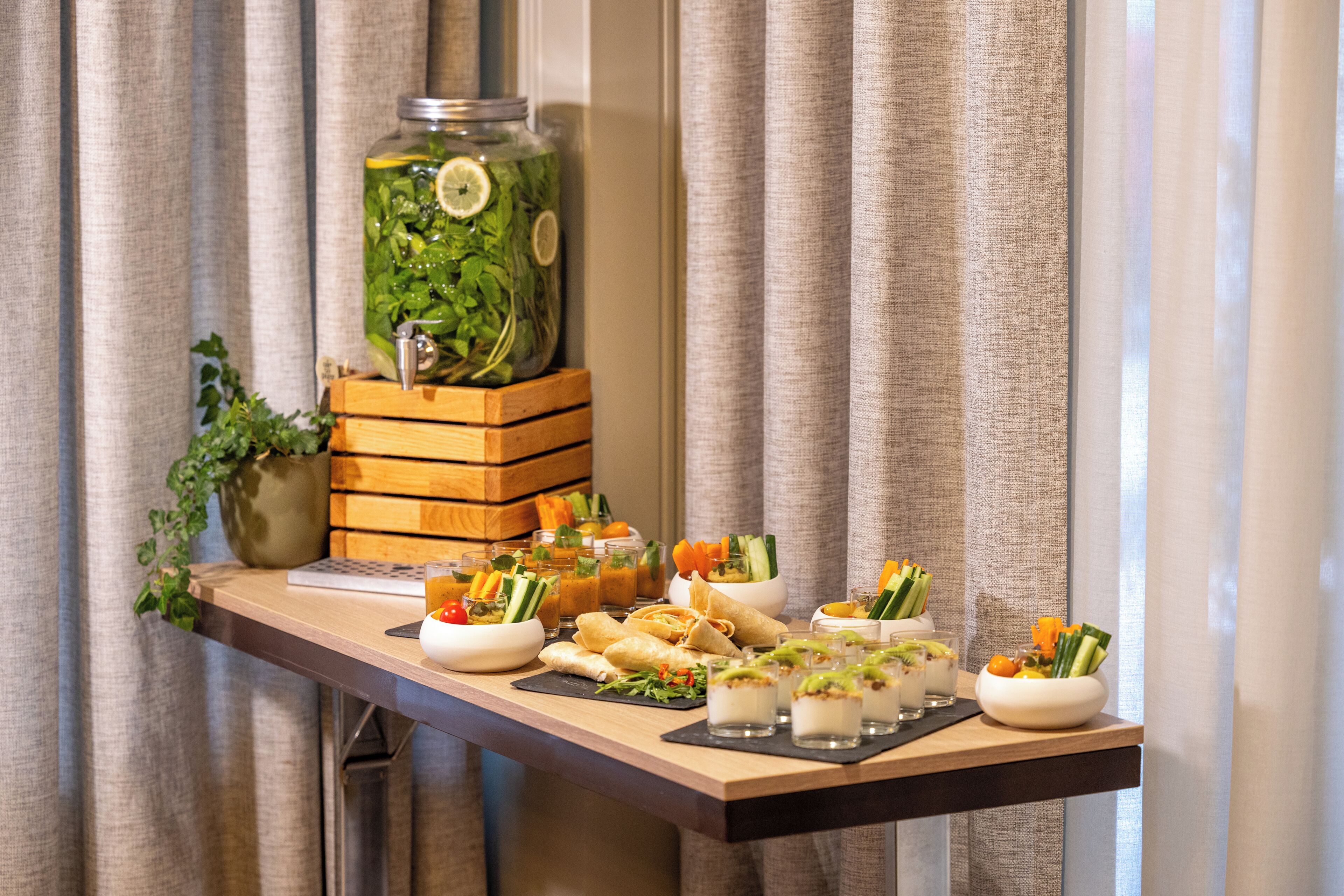 A buffet table with various food items and a large jar of pickled vegetables.