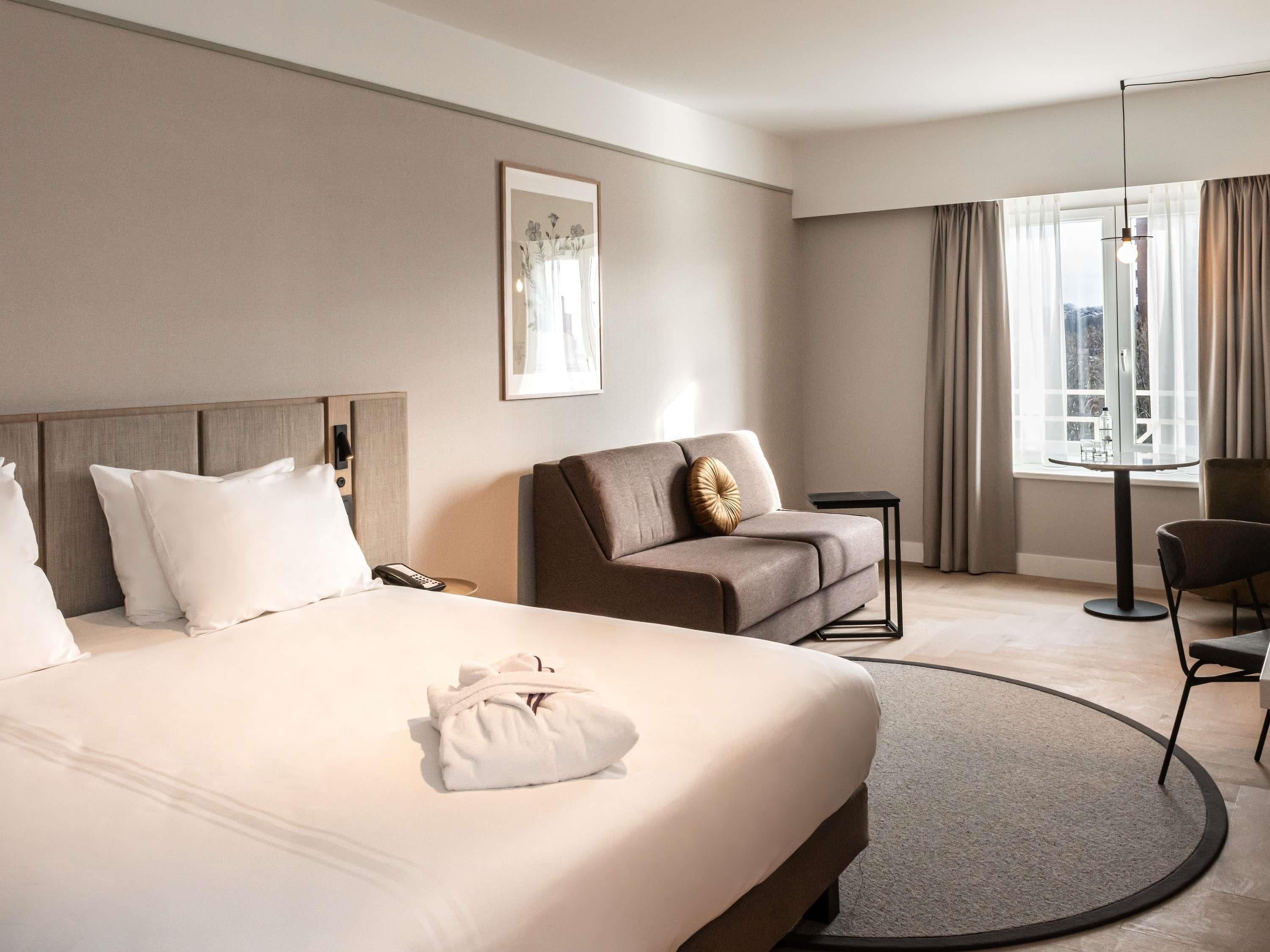Een hotelkamer met een bed, een bank, een klein tafeltje en een stoel.
