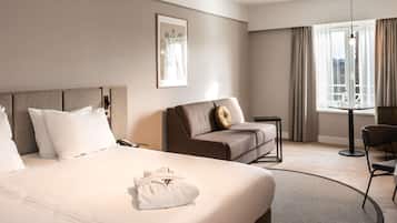 Een hotelkamer met een bed, een bank, een klein tafeltje en een stoel.