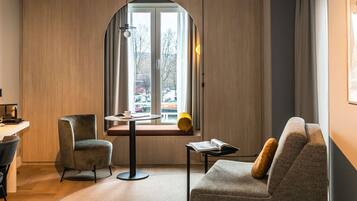 Une pièce moderne avec une fenêtre incurvée, une table ronde, un canapé et un fauteuil.