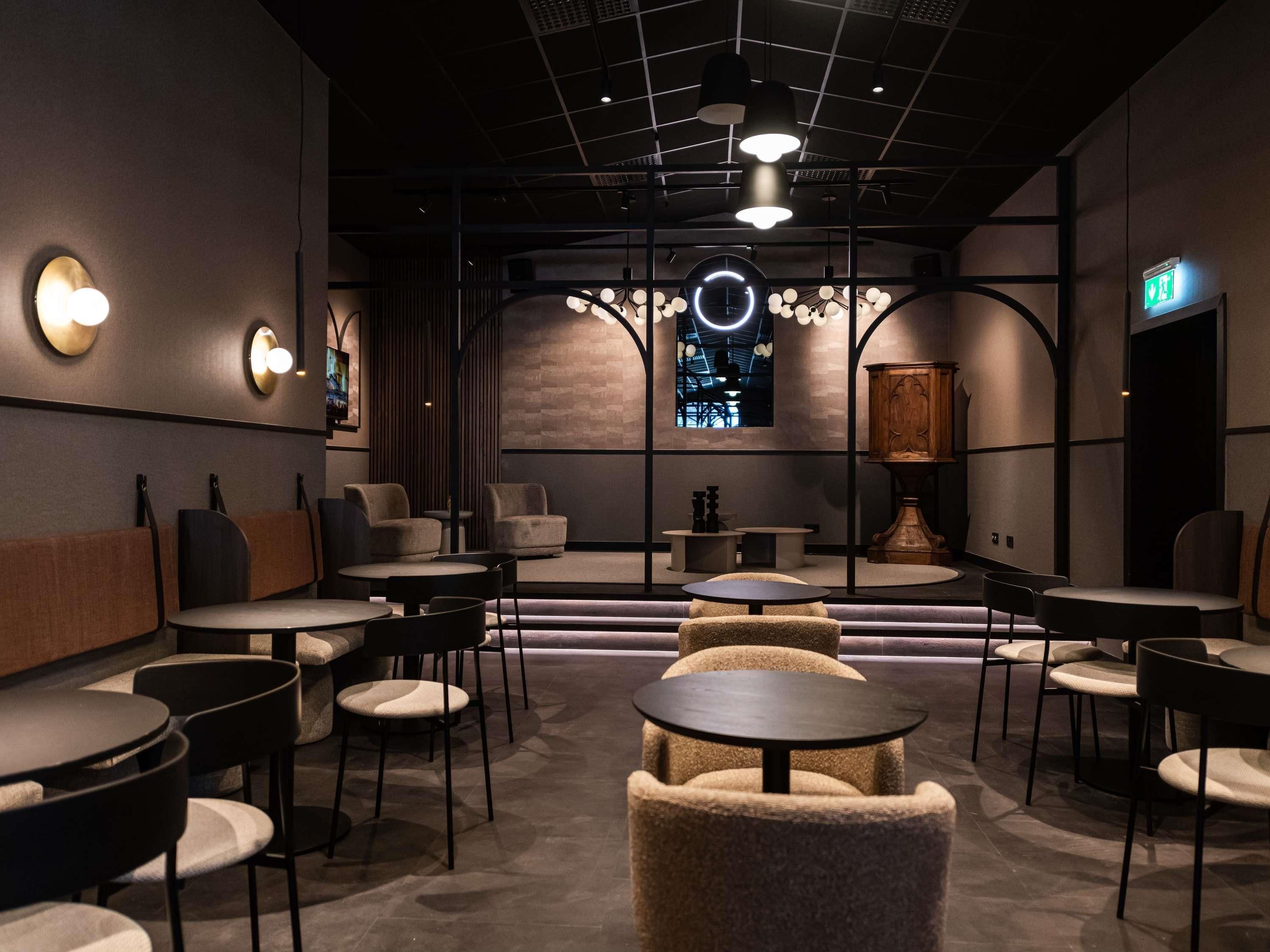 A modern interior with round tables, sofas, and a chandelier.