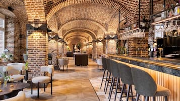 A bar area with brick walls, wooden bar counter, and bar stools.
