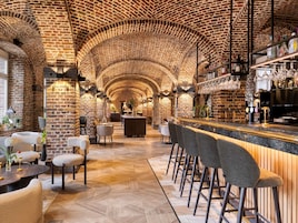 Zona de bar con paredes de ladrillo, mostrador de madera y taburetes.