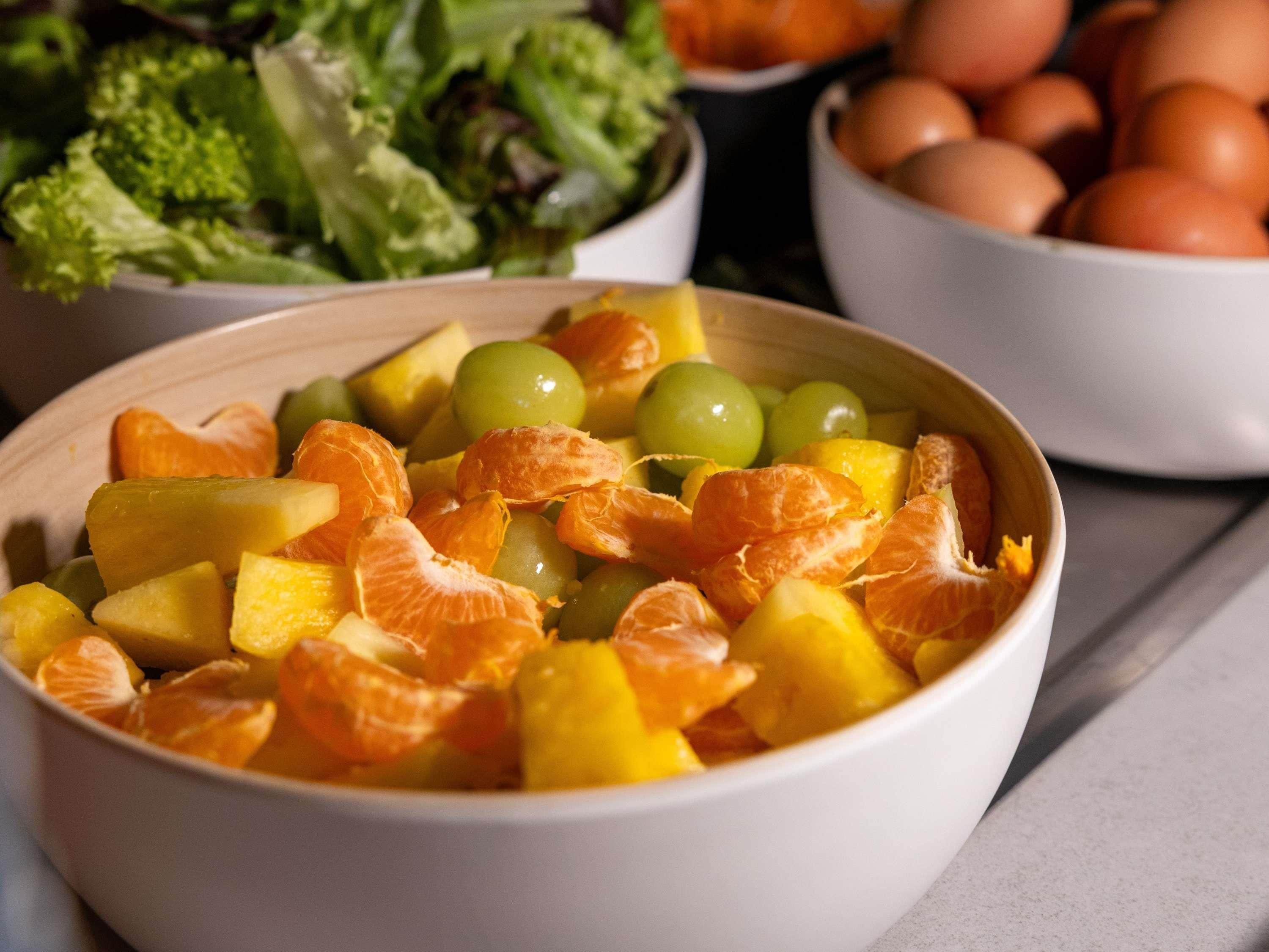 Een schaal fruitsalade met mandarijnen, druiven en ananasstukjes.