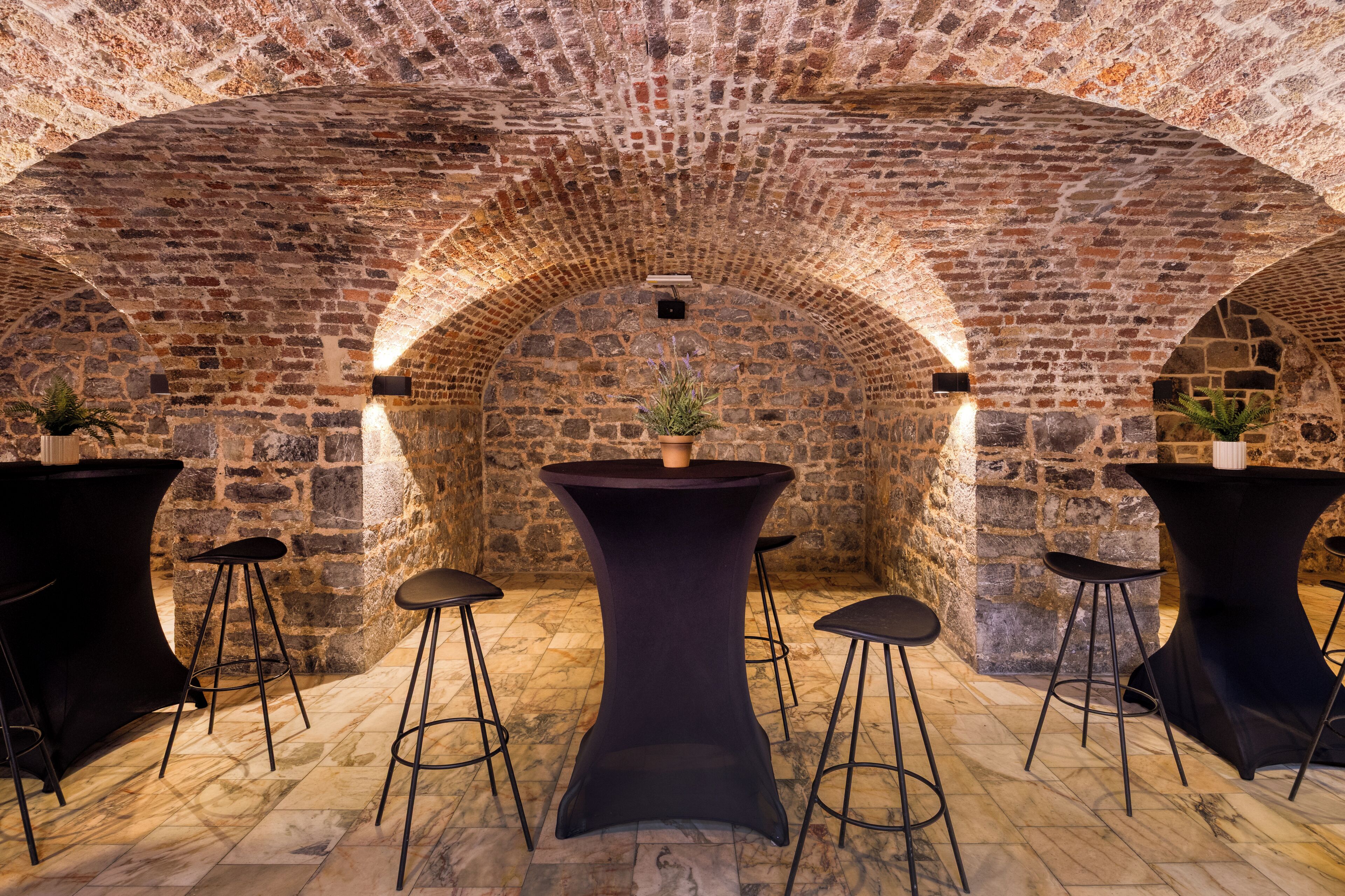 A stone-walled room with a central table and four stools.