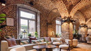 Un amplio salón con paredes de ladrillo, ventanas grandes y asientos cómodos.