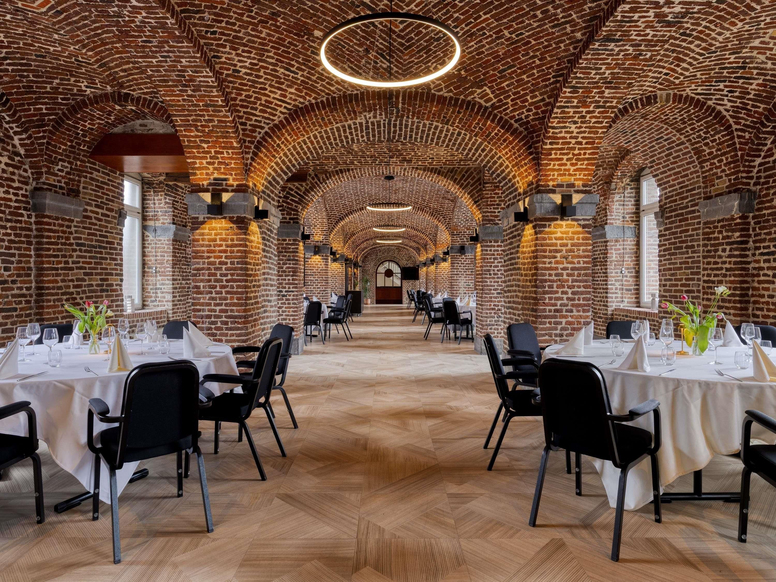 Un restaurante con arcos de ladrillo, suelo de madera y mesas dispuestas para comer.