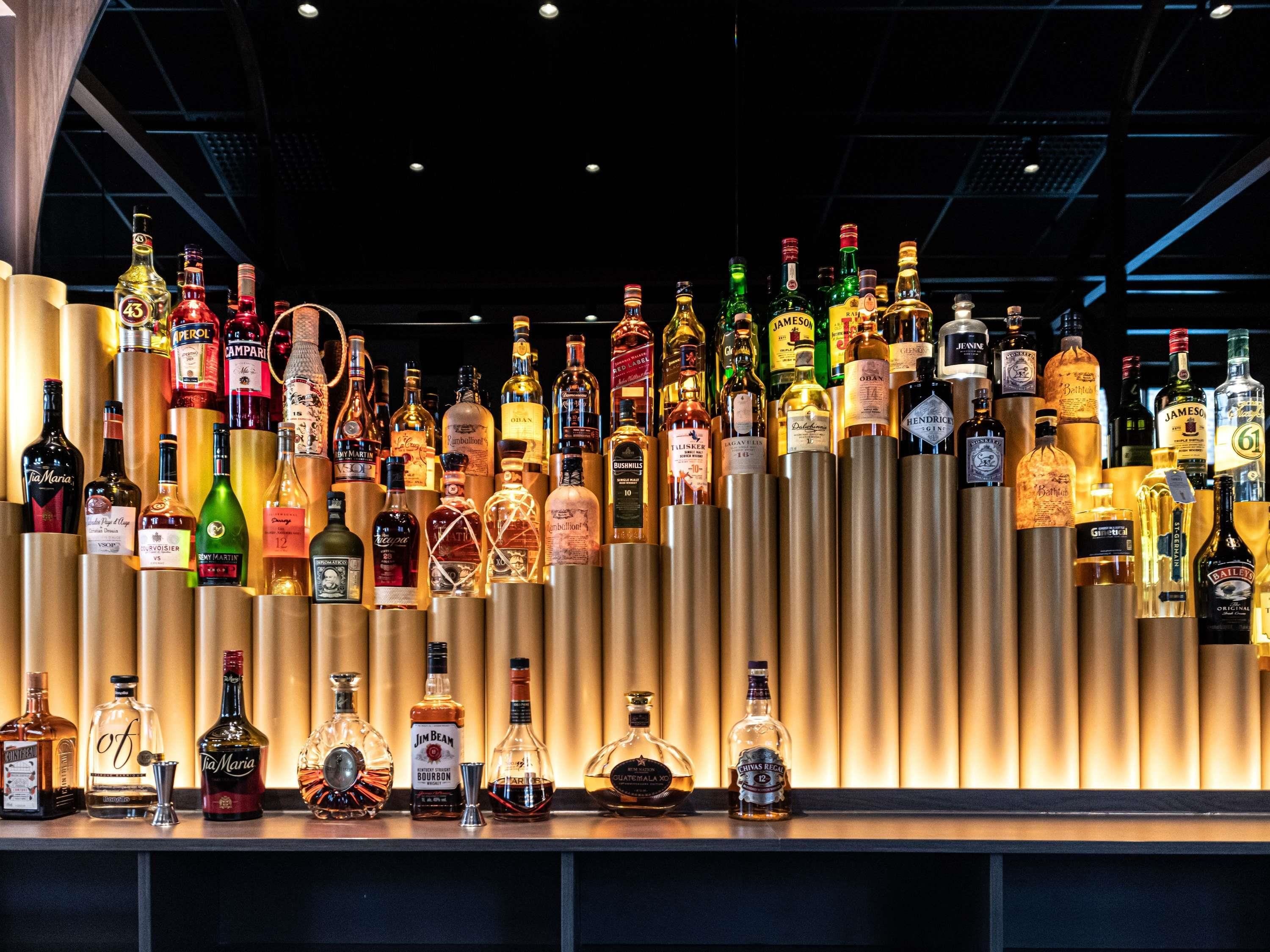 Um bar com diversas garrafas de bebidas alcoólicas expostas em prateleiras.