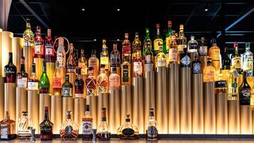 Um bar com diversas garrafas de bebidas alcoólicas expostas em prateleiras.
