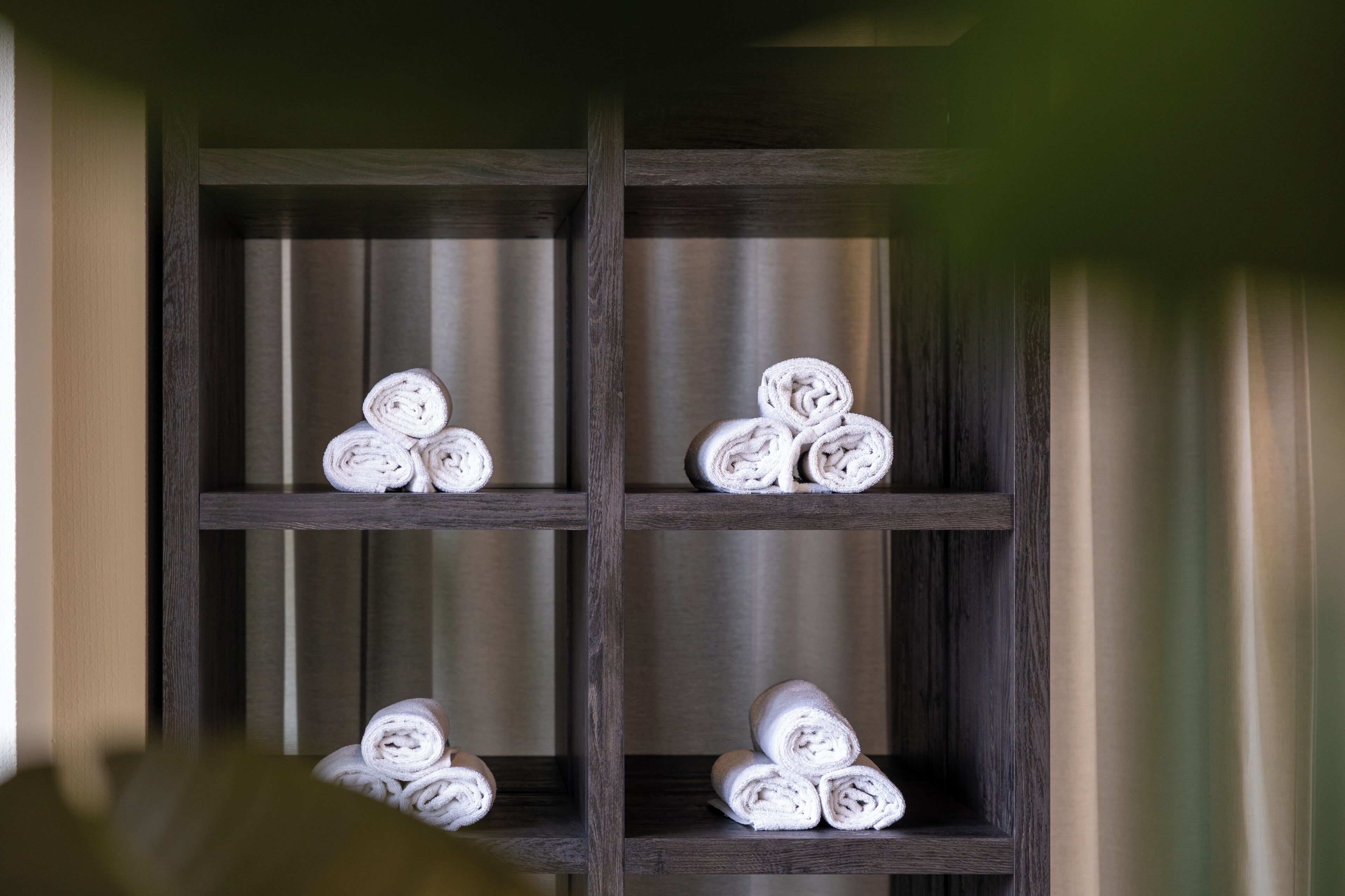 A wooden shelf with rolled towels.