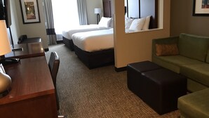Habitación de hotel con dos camas, un escritorio, un sofá y un espejo.