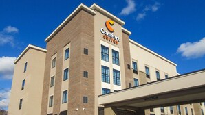Un hotel Comfort Suites con diseño moderno, que destaca un llamativo letrero de 'Comfort Suites' en el edificio.