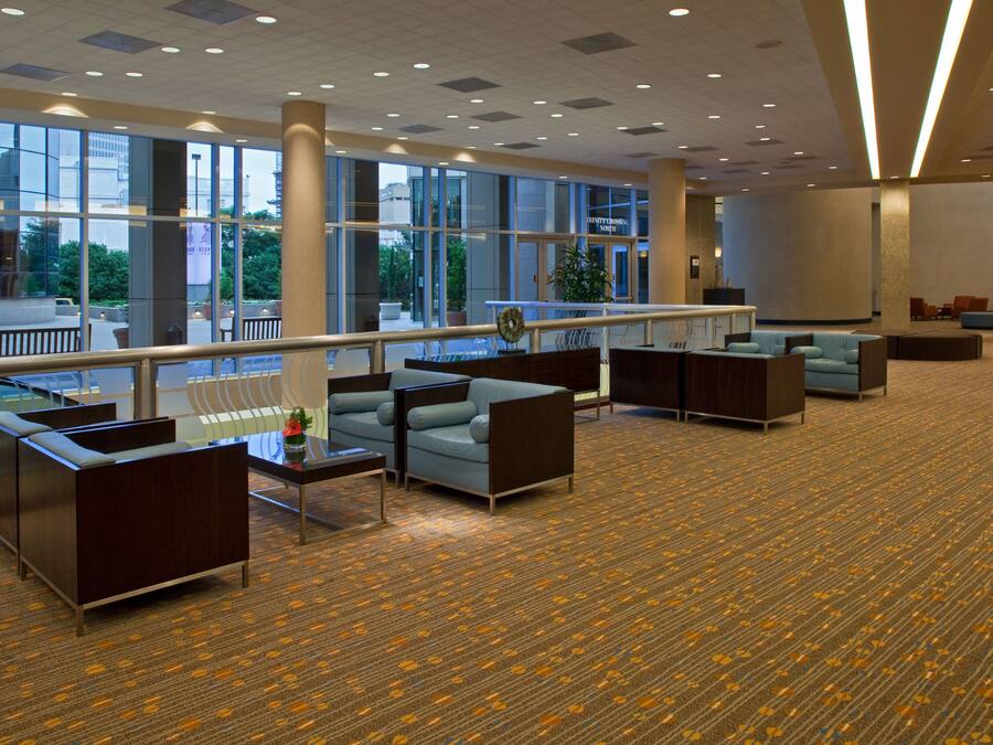 A spacious lobby with a carpeted floor, seating areas, and large windows offering views of the outdoors.