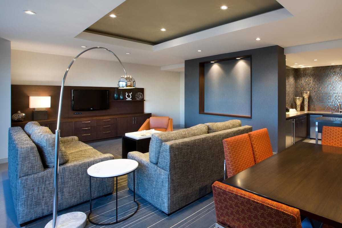 Un salon moderne comprenant un ensemble de canapés, une table à manger et un téléviseur fixé au mur.