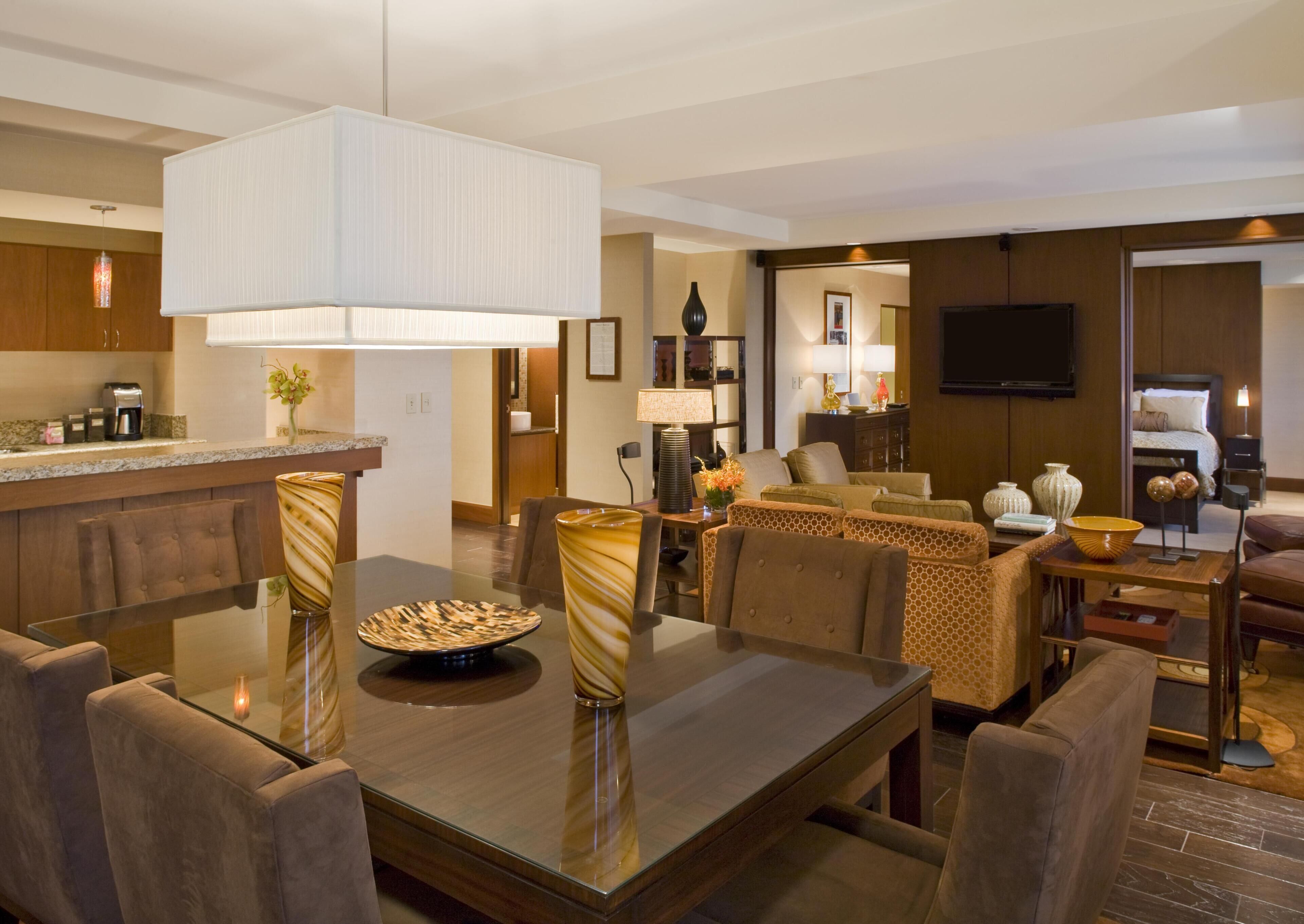 A modern hotel room with a dining area, a living room, and a kitchen.