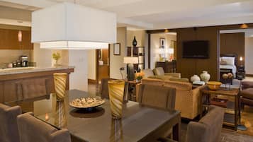 A modern hotel room with a dining area, a living room, and a kitchen.