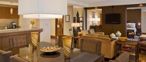 A modern hotel room with a dining area, a living room, and a kitchen.