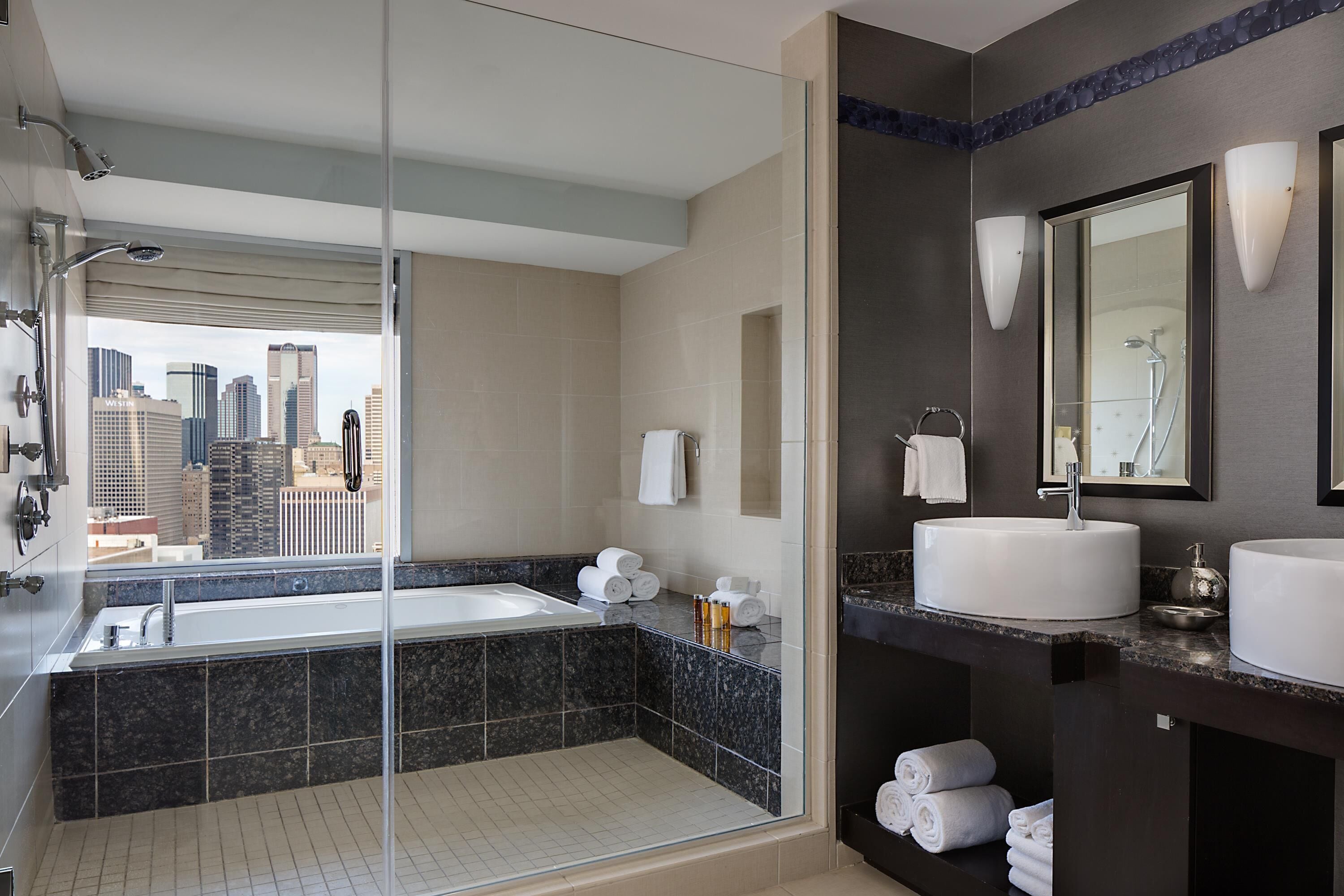 Un baño moderno con una bañera amplia, una zona de ducha separada y un tocador con lavabo y espejo.